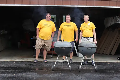 three men in standing behind a grill