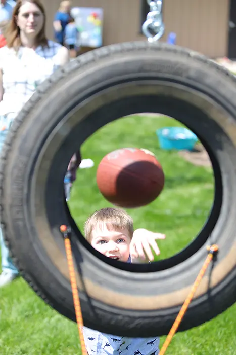 Child throwing a football through a tire