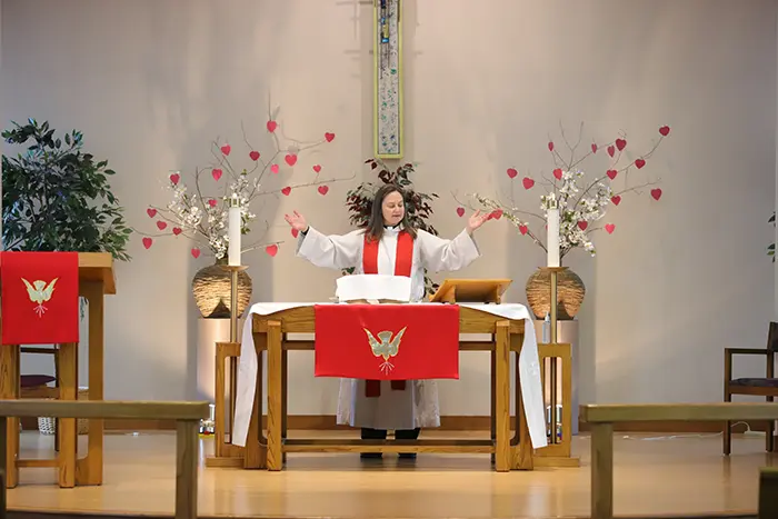 Pastor Tabitha standing with arms outstretched behind the pulpit